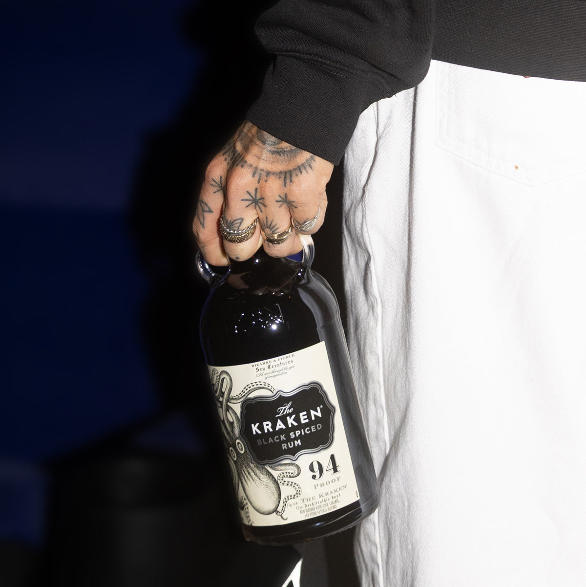 Lifestyle image of model holding The Kraken Black Spiced Rum bottle