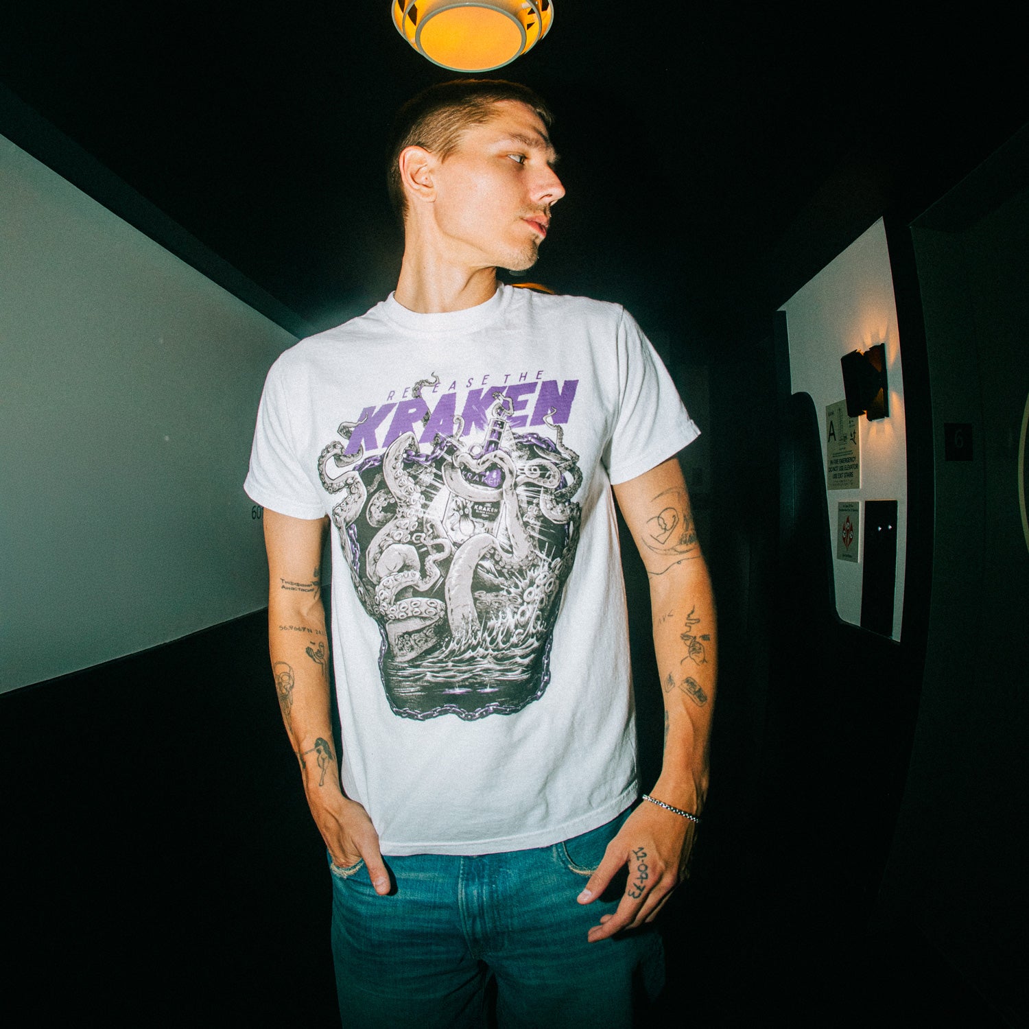 The image features a person standing indoors wearing the Artist of the Abyss tee.