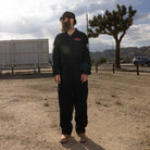 A front view lifestyle image of the Beware The Kraken Coveralls on a male model in the desert