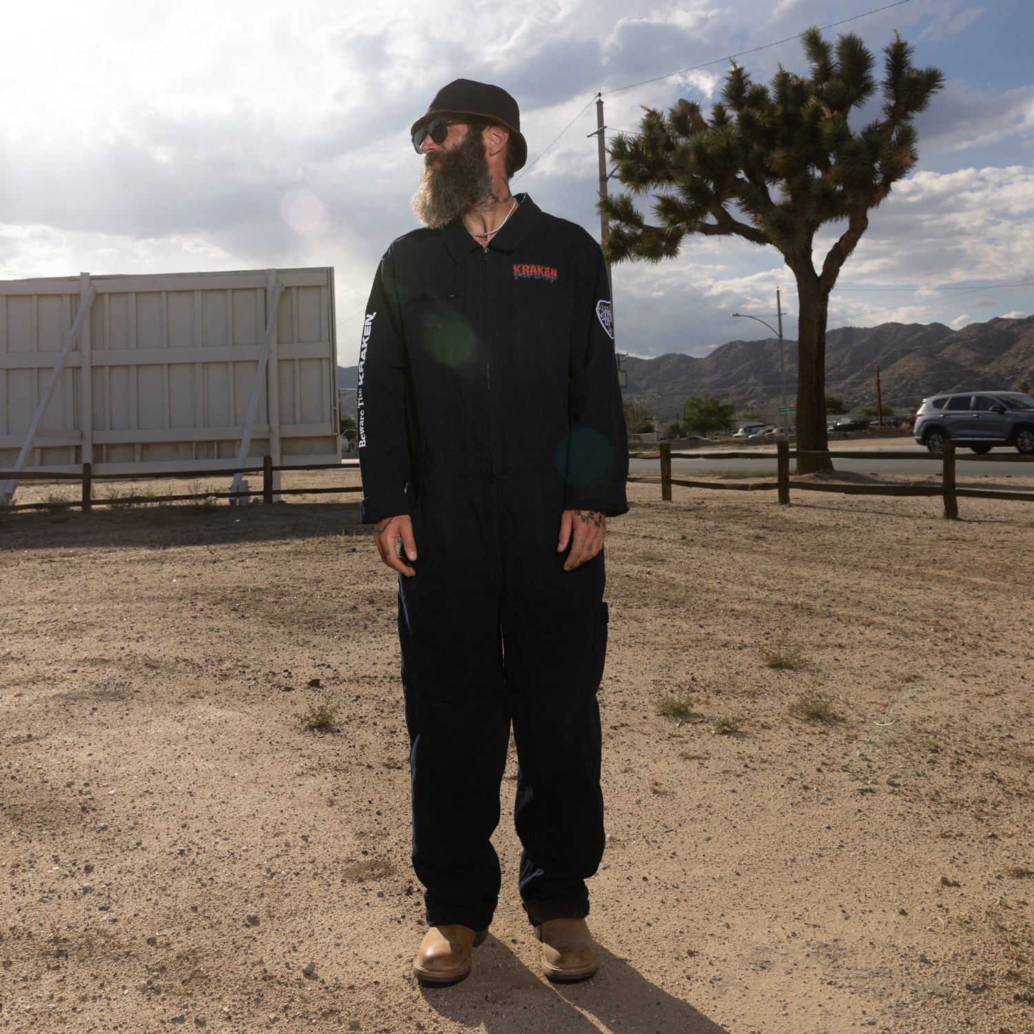 A front view lifestyle image of the Beware The Kraken Coveralls on a male model in the desert