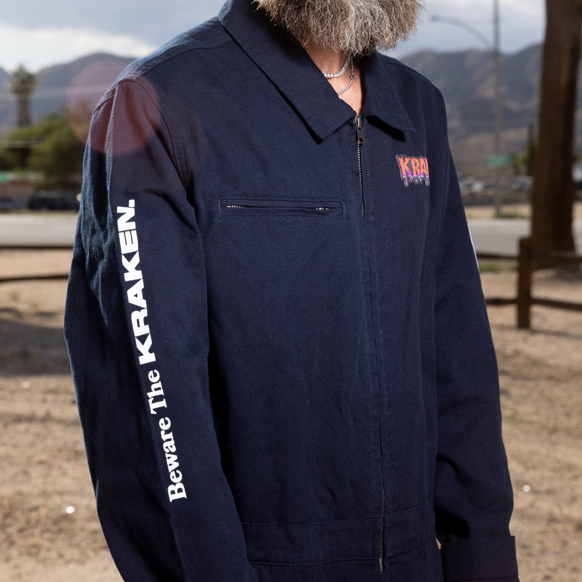 A side view lifestyle image of the Beware The Kraken Coveralls on a male model in the desert