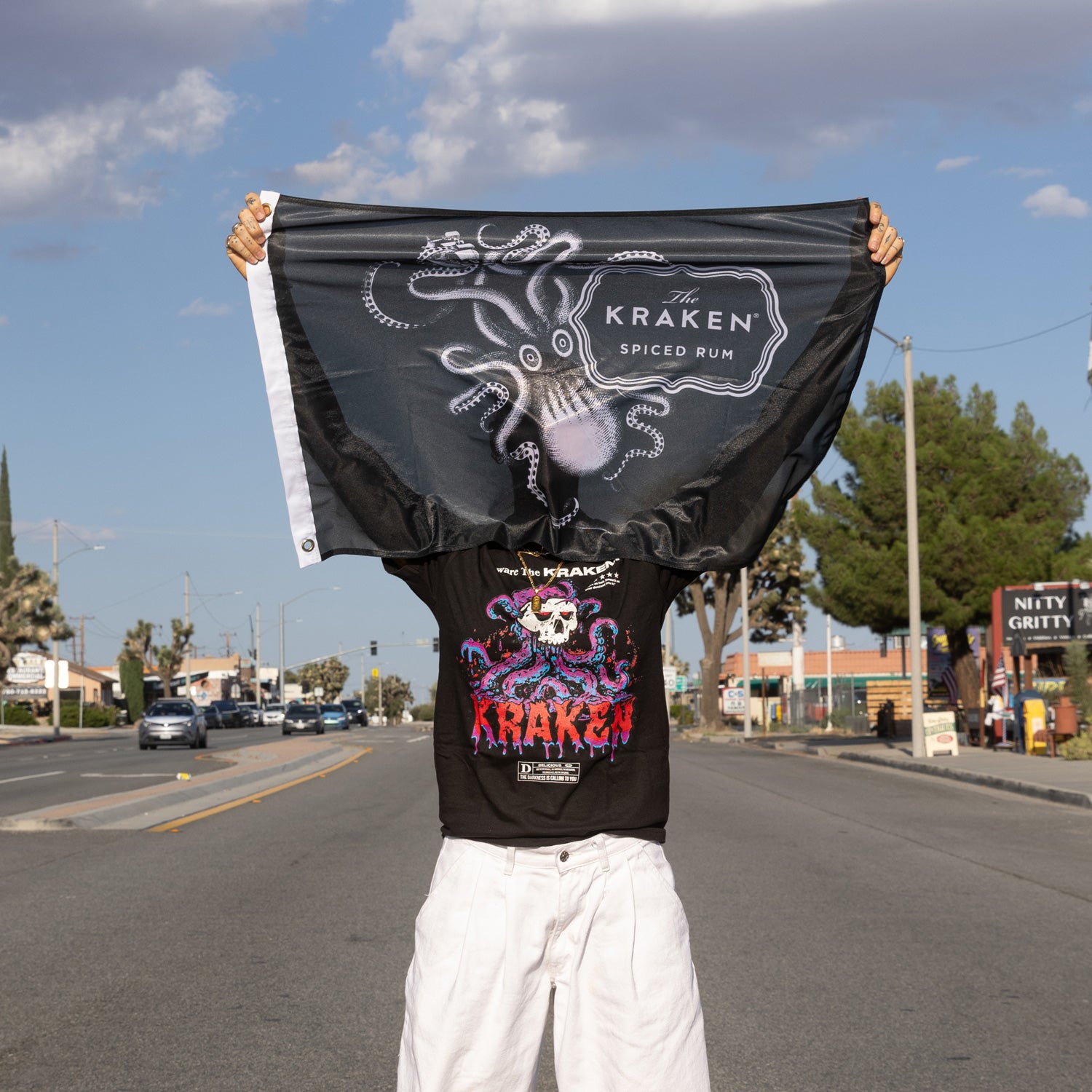 A lifestyle image of a model holding up The Kraken flag in the middle of the middle of the street.