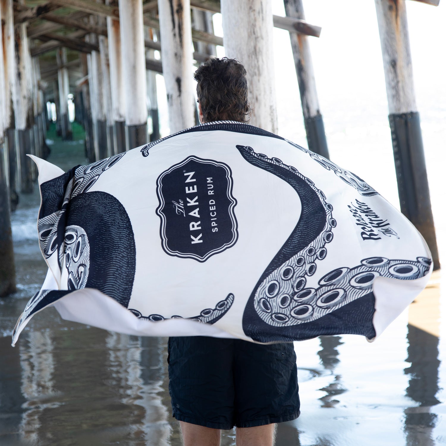 Person holding a Kraken Spiced Rum branded towel on a pier