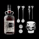 Kraken Black Spiced Rum bottle with skull-shaped glass and decorative spoons on a black background