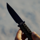 Knife with textured handle held by a hand against a blurred background