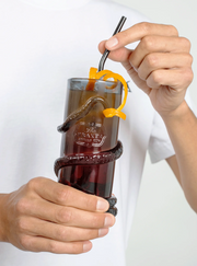 A man's hand inserts a metal straw into a Kraken Tentacle Cocktail glass.